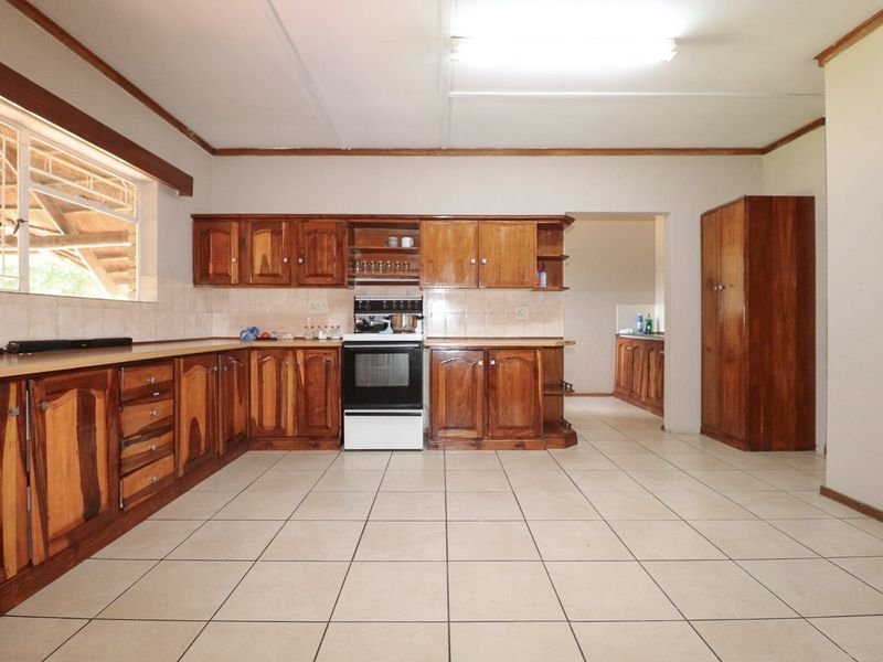 Spacious kitchen featuring traditional wooden cabinetry, tiled flooring, and a freestanding stove, offering a functional layout with potential for modern updates.