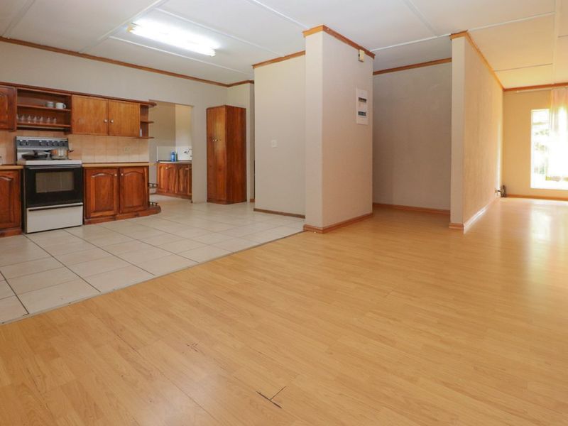 Open plan living and kitchen area featuring wooden cabinetry, a freestanding stove, tiled kitchen flooring, and laminate flooring in the living space.