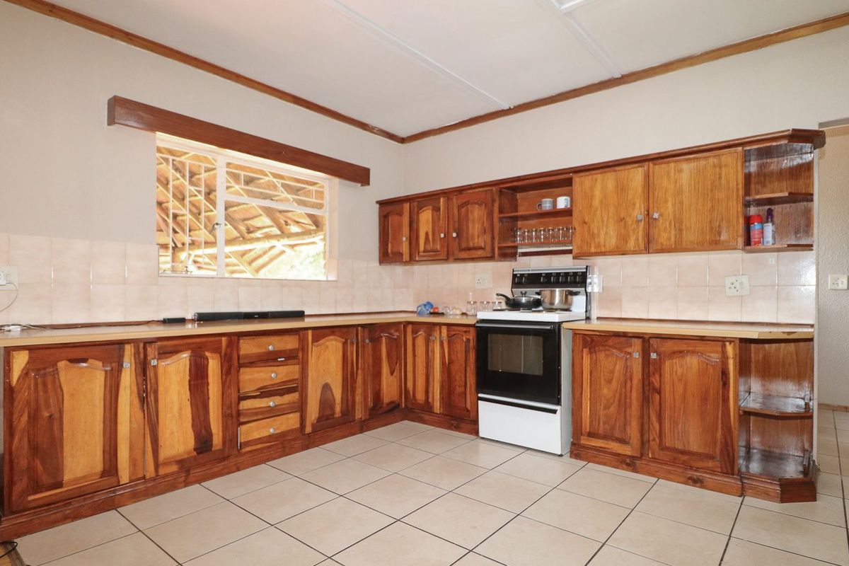 A functional kitchen featuring traditional wooden cabinetry, tiled flooring, and a freestanding oven, offering a classic layout with potential for modern updates.
