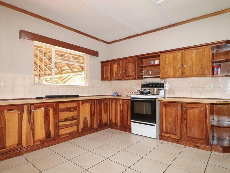 A functional kitchen featuring traditional wooden cabinetry, tiled flooring, and a freestanding oven, offering a classic layout with potential for modern updates.
