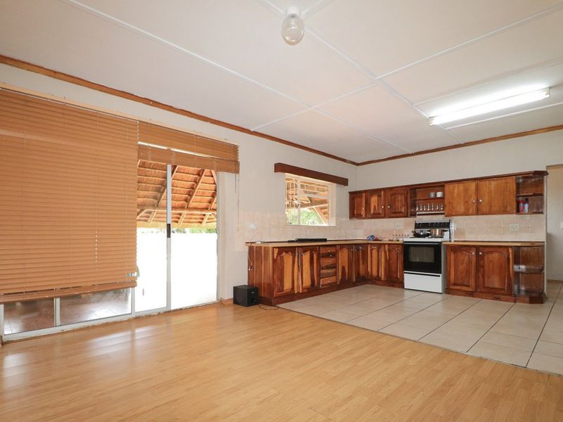 Open-plan kitchen and living area featuring wooden cabinetry, tiled kitchen flooring, and direct access to an outdoor patio through sliding glass doors.