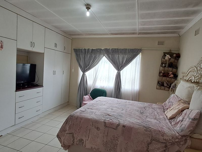 A bedroom featuring built-in cupboards, tiled flooring, and a window with curtains. The room offers functional storage space and neutral finishes.
