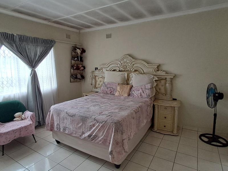 A bedroom featuring tiled flooring and a window with a security gate. The ceiling shows visible signs of water damage and cracking.