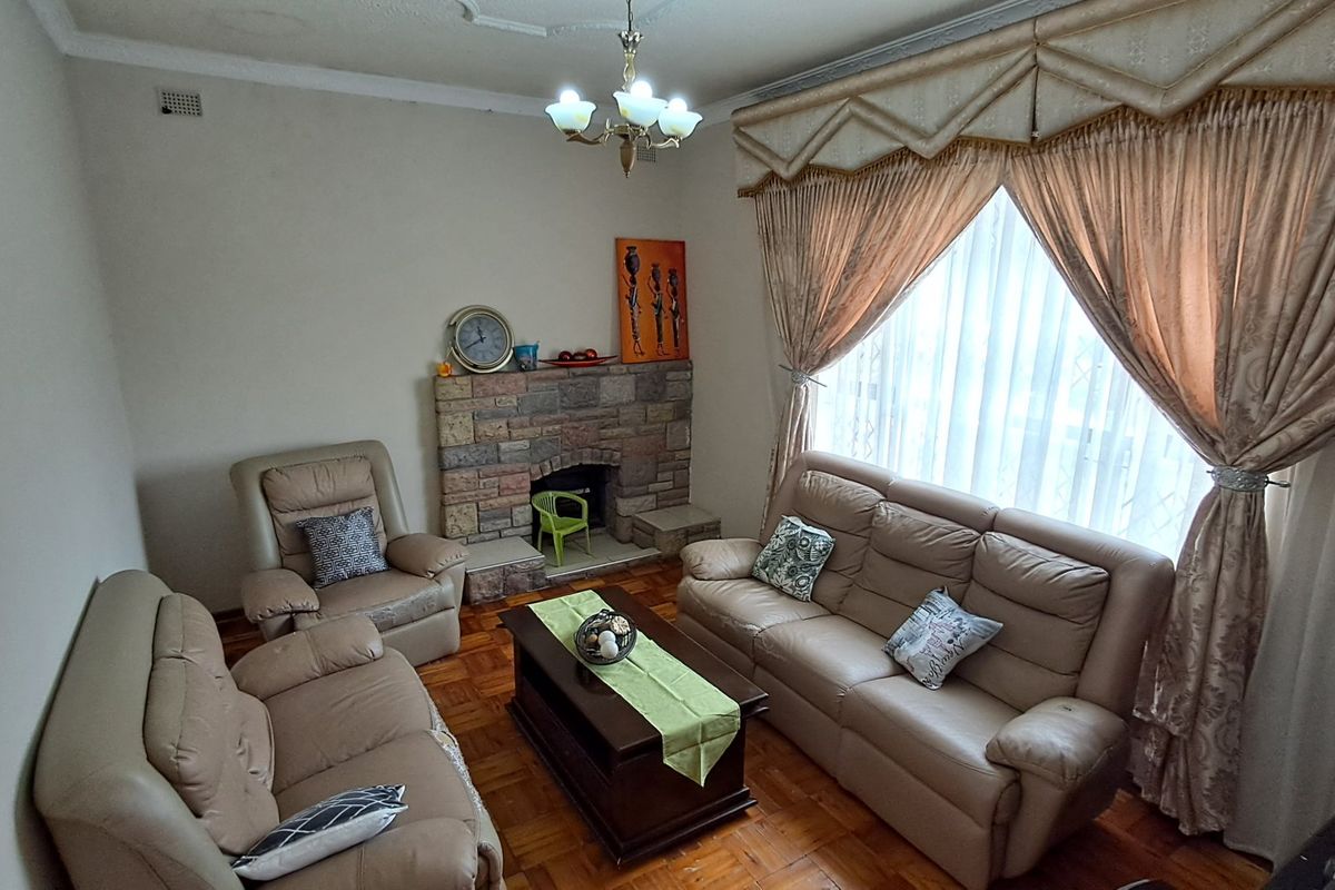 A traditional living room featuring a stone fireplace, parquet flooring, and decorative ceiling detailing, offering a warm and classic atmosphere.