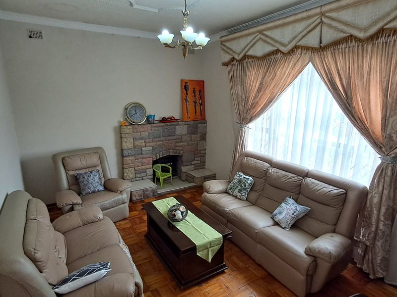A traditional living room featuring a stone fireplace, parquet flooring, and decorative ceiling detailing, offering a warm and classic atmosphere.