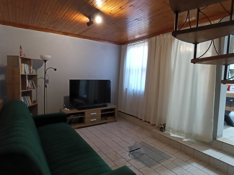 Living room featuring ceramic floor tiles and a timber ceiling, with an adjacent staircase leading to another level.
