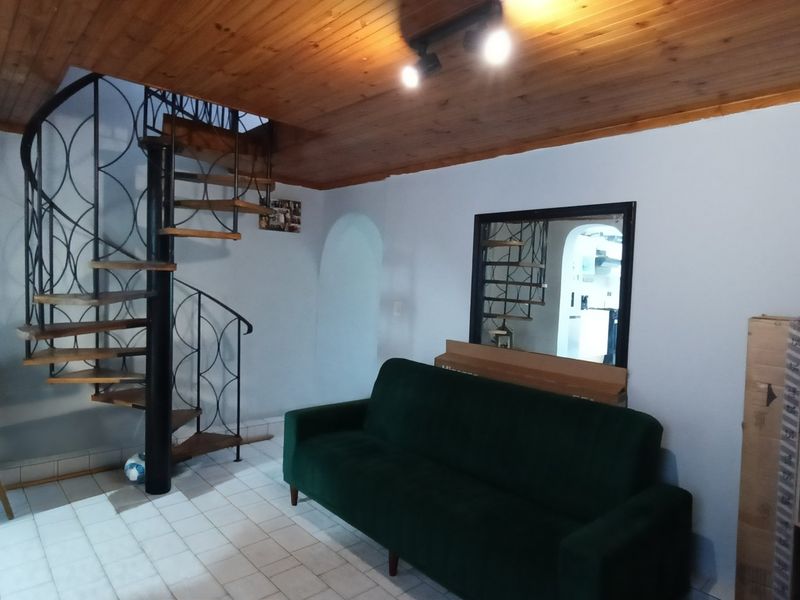 Living area featuring a distinctive spiral staircase, timber-clad ceiling, and tiled flooring, providing a unique architectural focal point.