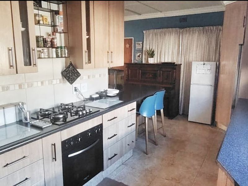 A functional kitchen featuring light wood-finish cabinetry, a gas hob, built-in oven, and tiled backsplash with ample counter space.
