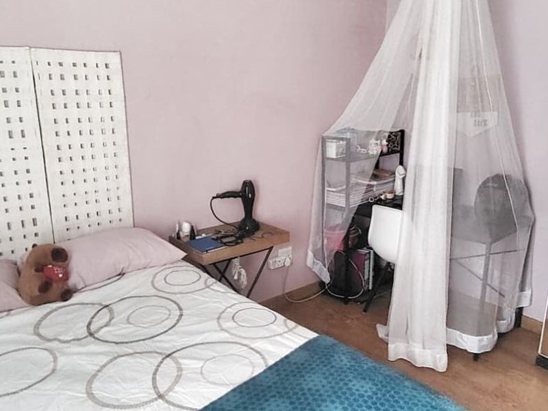 A bedroom featuring laminate flooring and a standard door, providing a functional living space.