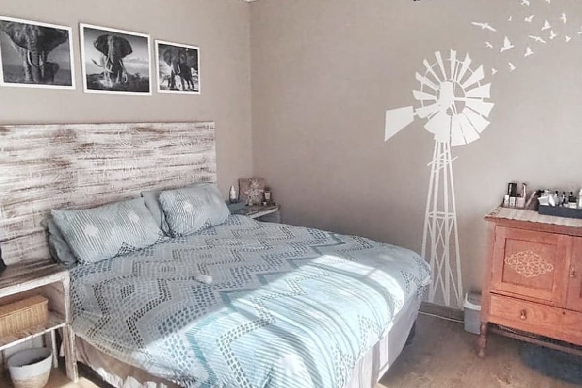A cozy bedroom featuring laminate flooring and a wall-mounted fan, offering a comfortable and functional sleeping space.