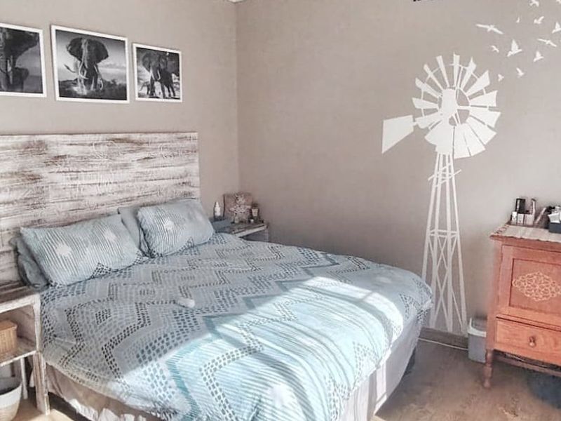 A cozy bedroom featuring laminate flooring and a wall-mounted fan, offering a comfortable and functional sleeping space.