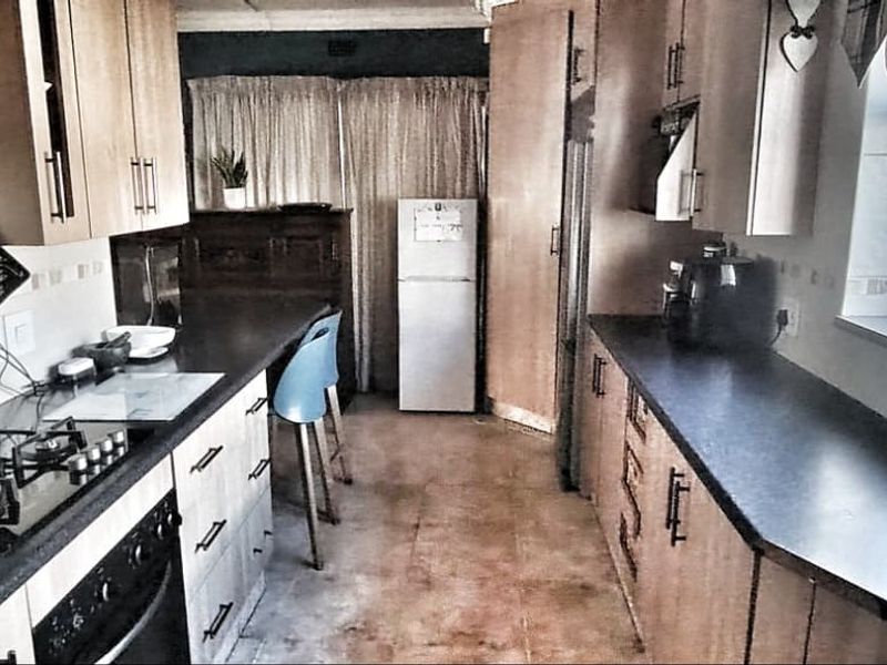 A functional galley-style kitchen featuring built-in cabinetry, a gas hob, and oven with ample counter space and natural light.