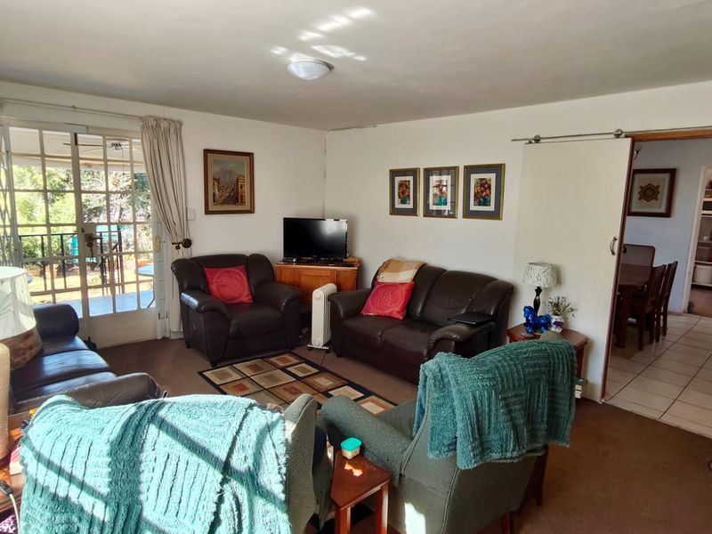 A comfortable living room featuring a sliding glass door with security gate, providing access to the outdoor area and connecting to the adjacent dining space.