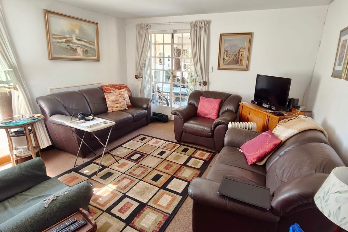 A comfortable living room featuring carpeted flooring and glass-paned french doors that provide natural light and access to the outdoor area.