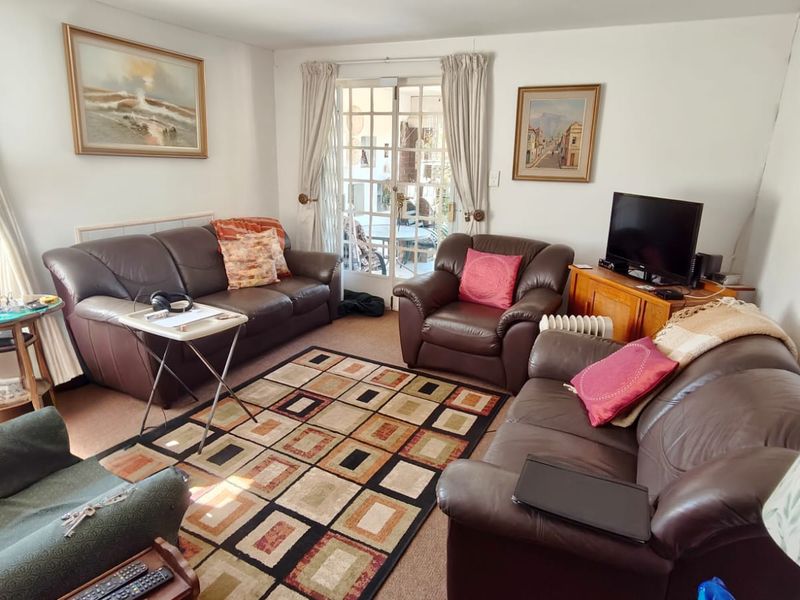 A comfortable living room featuring carpeted flooring and glass-paned french doors that provide natural light and access to the outdoor area.