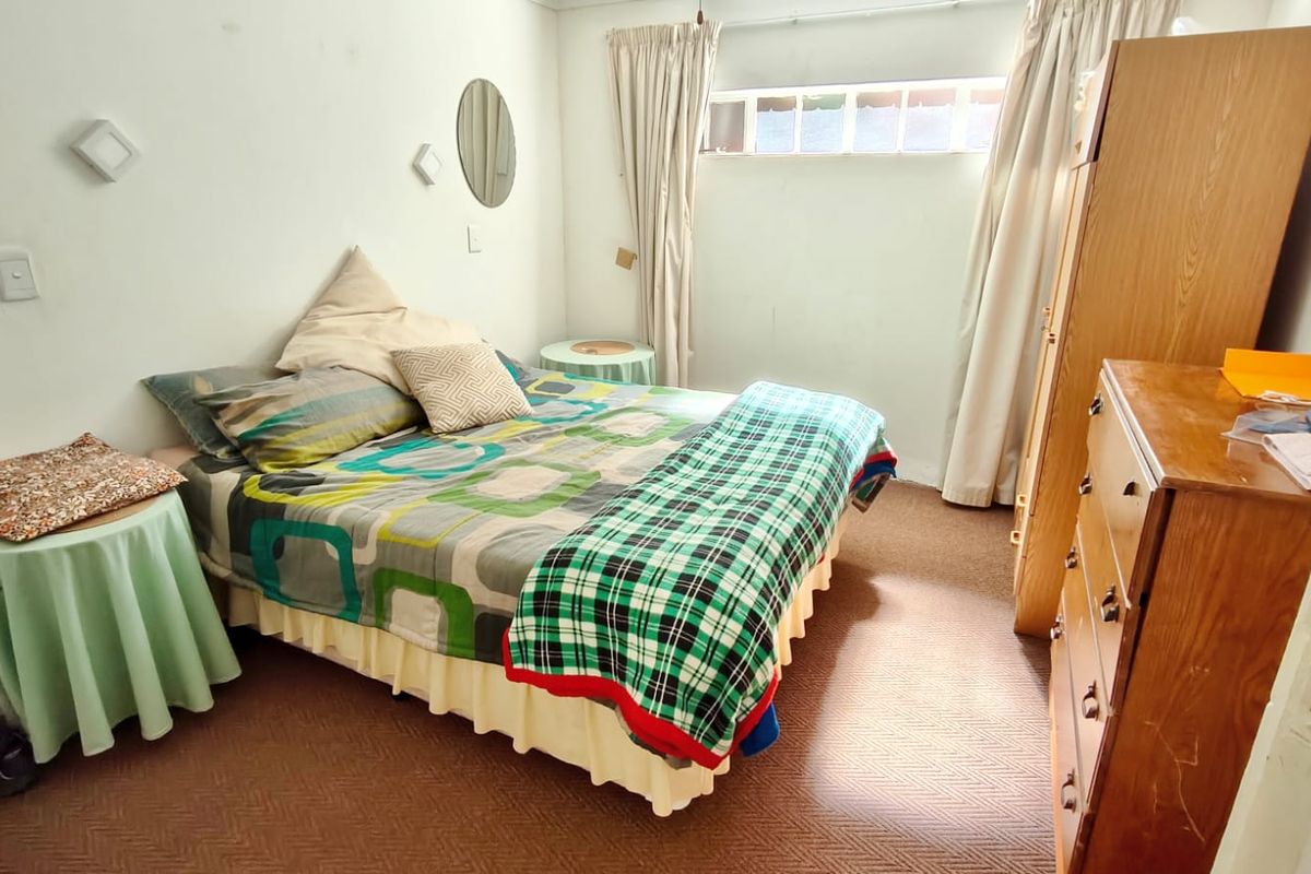 A bedroom featuring carpeted flooring and a high-level window, currently requiring cosmetic updates to the wall finishes and flooring.