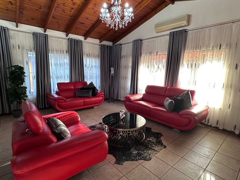 Spacious living room featuring a high exposed timber raked ceiling, tiled flooring, and a split-system air conditioner, offering a bright and airy atmosphere.