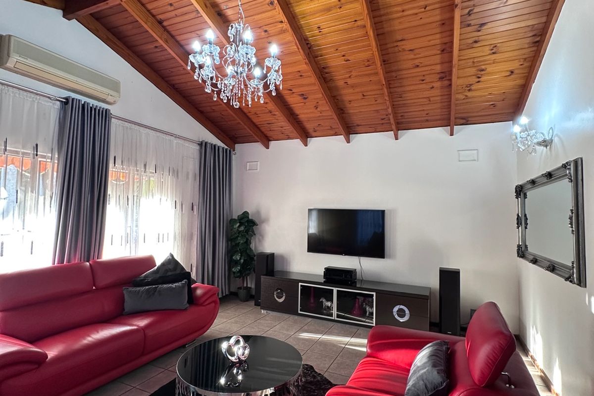 Spacious living room featuring a high vaulted timber ceiling, tiled flooring, and a wall-mounted air conditioning unit.