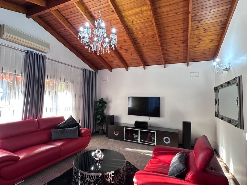 Spacious living room featuring a high vaulted timber ceiling, tiled flooring, and a wall-mounted air conditioning unit.