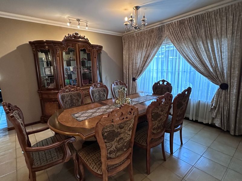 A formal dining room featuring tiled flooring, decorative ceiling lighting, and large window treatments, providing a traditional space for family meals and entertaining.