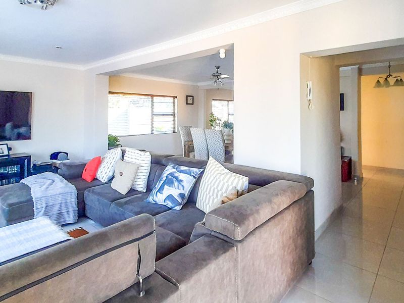 Spacious open-plan living area featuring neutral walls, tiled flooring, and decorative ceiling cornicing, connecting seamlessly to the adjacent dining space.