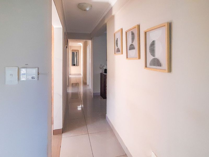 A bright and clean hallway featuring neutral walls, tiled flooring, and a built-in security alarm system.