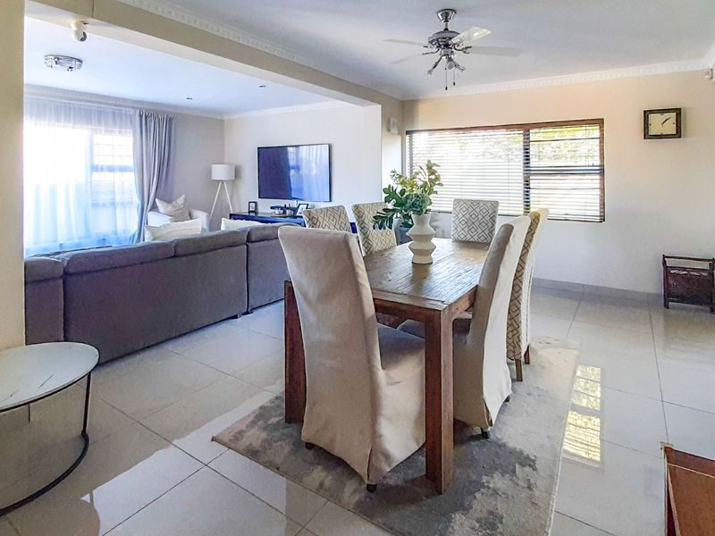 Spacious open-plan living and dining area featuring tiled flooring, ceiling fan, and neutral finishes, creating a bright and functional family space.