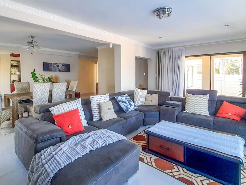 Spacious open-plan living and dining area featuring tiled floors, decorative ceiling cornices, and large sliding glass doors providing natural light.