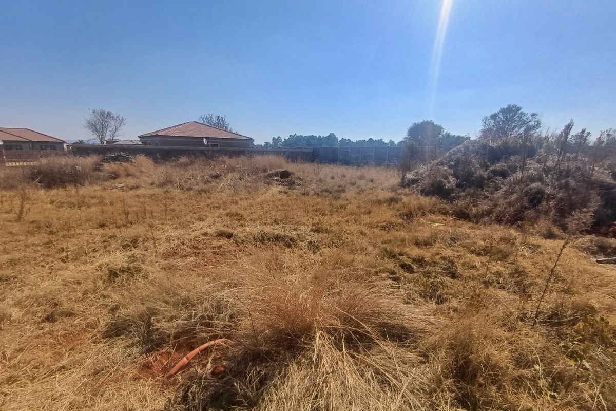 A vacant residential plot featuring dry, overgrown grass and perimeter boundary walls, offering a blank canvas for future development.