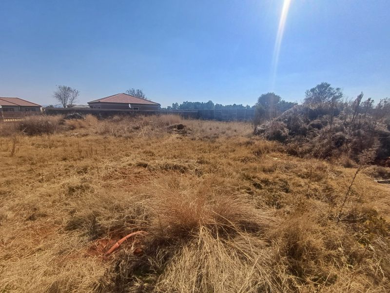 A vacant residential plot featuring dry, overgrown grass and perimeter boundary walls, offering a blank canvas for future development.