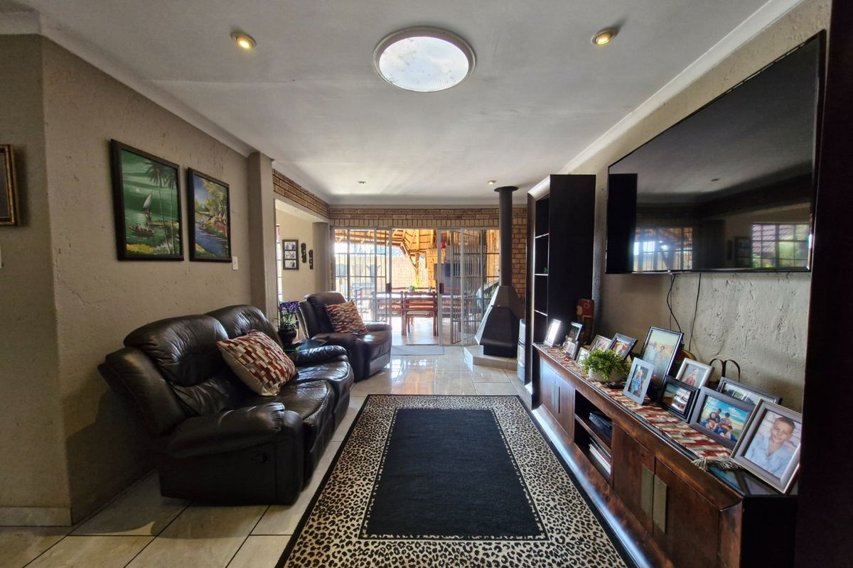 Spacious living room featuring a central freestanding fireplace, tiled flooring, and a skylight, with direct access to an outdoor patio area.