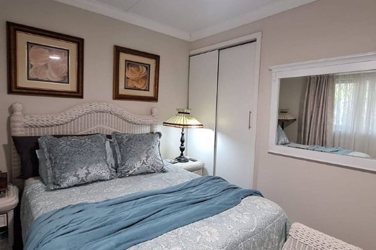 A well-maintained bedroom featuring a built-in wardrobe, decorative coving, and a large wall-mounted mirror, creating a bright and functional living space.