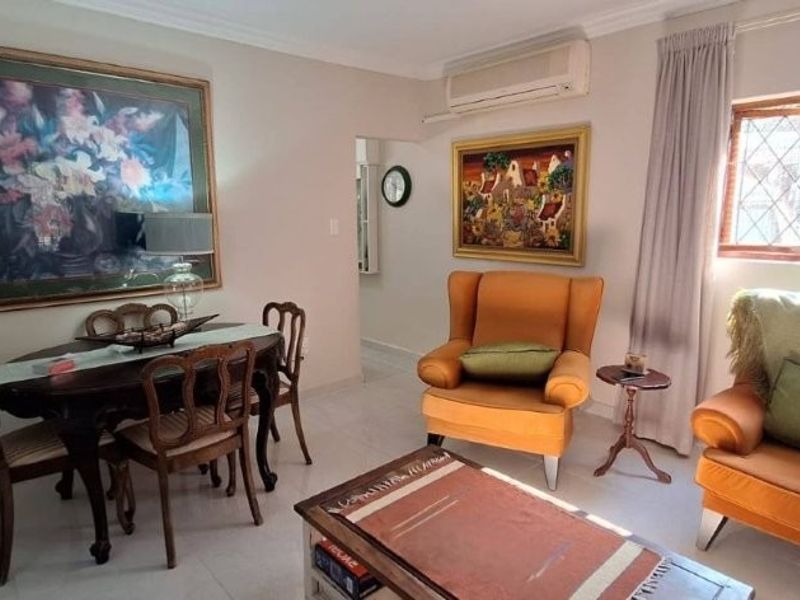 A well-maintained living room featuring tiled flooring, coving, and a wall-mounted split-system air conditioning unit.
