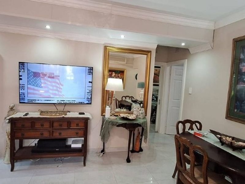 A living area featuring tiled flooring, recessed downlighting, and crown molding, providing a functional space with traditional interior finishes.