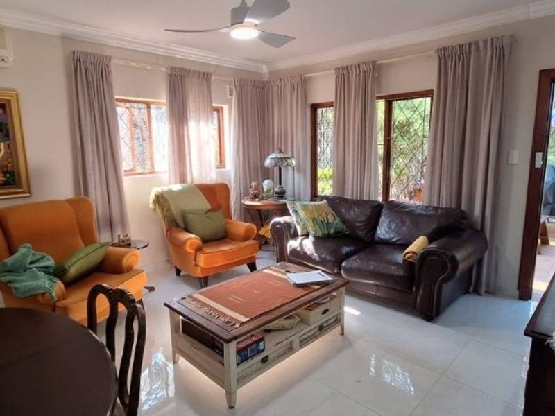 A well-maintained living room featuring tiled flooring, a ceiling fan, and a split-system air conditioner, with direct access to the outdoor patio area.