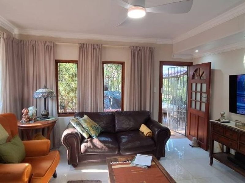 A comfortable living room featuring tiled flooring, recessed lighting, a ceiling fan, and direct access to the exterior through a timber security door.