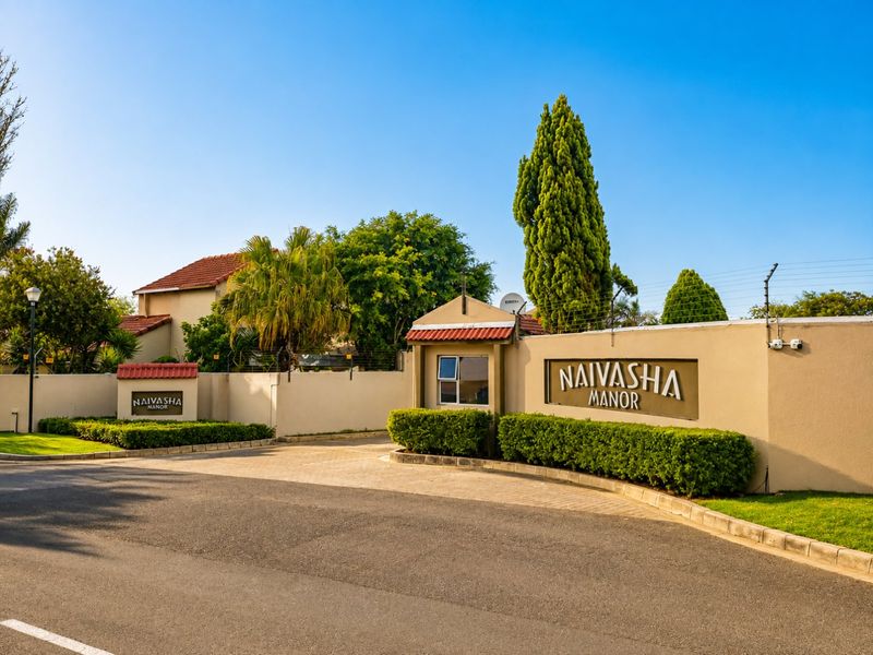The entrance to Naivasha Manor featuring a secure gatehouse, perimeter wall with electric fencing, and well-maintained landscaped gardens.