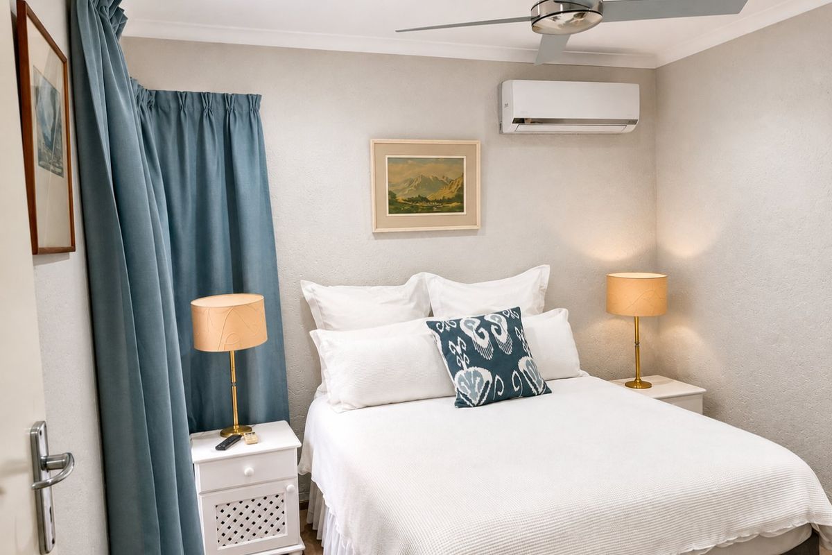 A well-maintained bedroom featuring a ceiling fan, split-system air conditioning, and recessed lighting, offering a comfortable and functional living space.