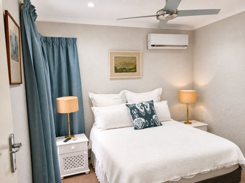 A well-maintained bedroom featuring a ceiling fan, split-system air conditioning, and recessed lighting, offering a comfortable and functional living space.