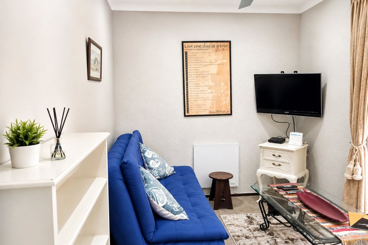 A compact living room featuring neutral walls, recessed ceiling lighting, a ceiling fan, and a wall-mounted electric heater.