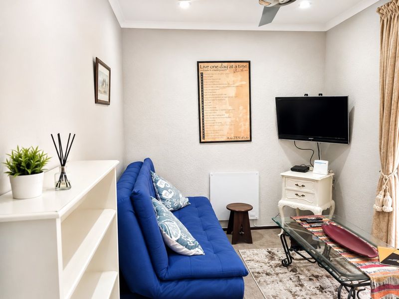 A compact living room featuring neutral walls, recessed ceiling lighting, a ceiling fan, and a wall-mounted electric heater.