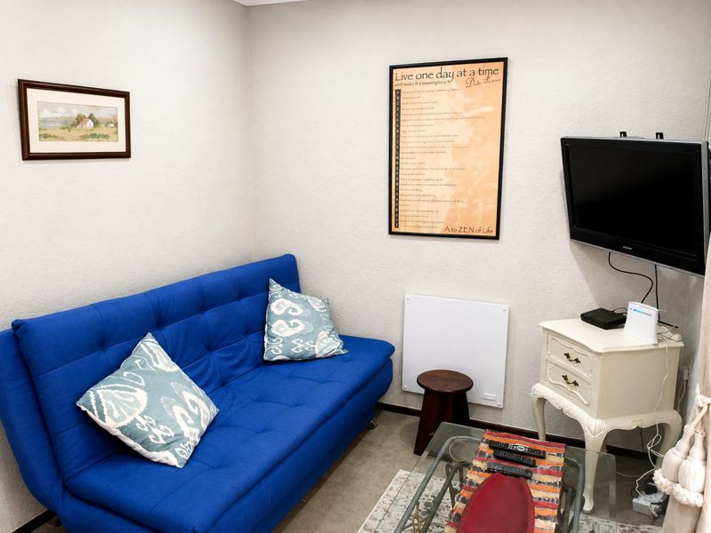 A compact living area featuring a wall-mounted electric heater and television mount, providing a functional space for relaxation.