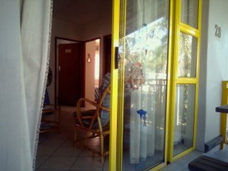 View from a patio through a yellow-framed sliding glass door into the interior of the apartment.