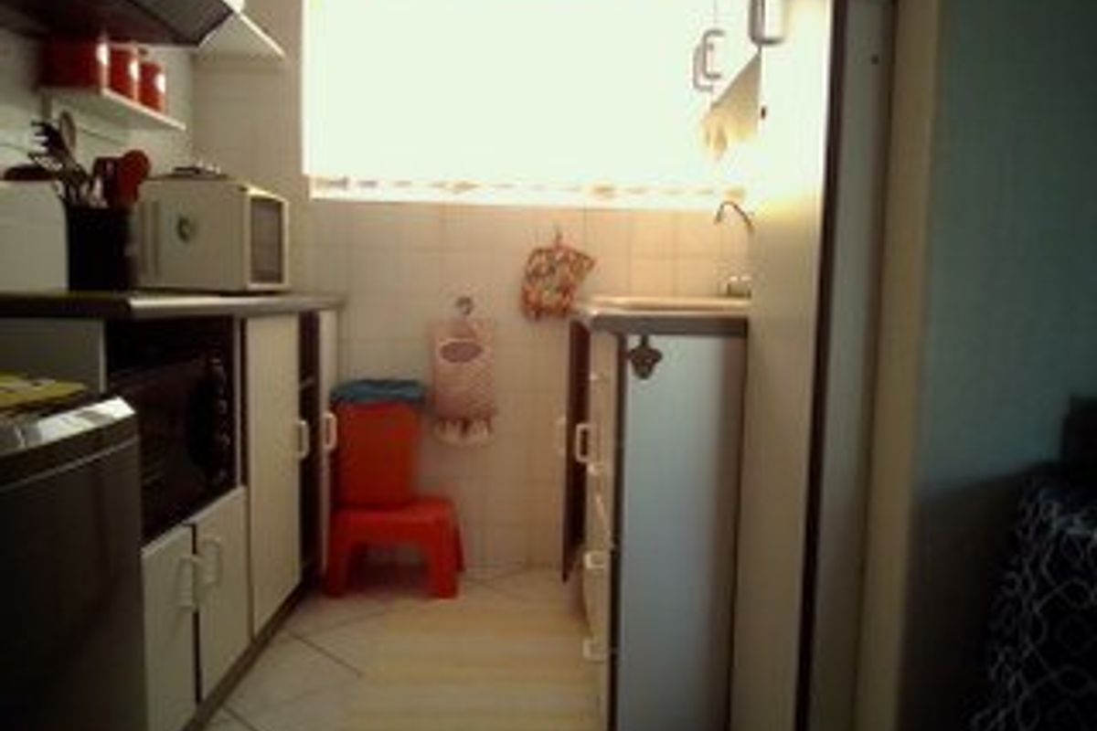 A compact kitchen featuring built-in cabinetry, tiled backsplash, and tiled flooring, requiring modernization to improve functionality and aesthetic appeal.