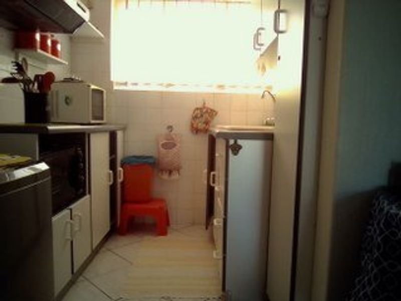 A compact kitchen featuring built-in cabinetry, tiled backsplash, and tiled flooring, requiring modernization to improve functionality and aesthetic appeal.