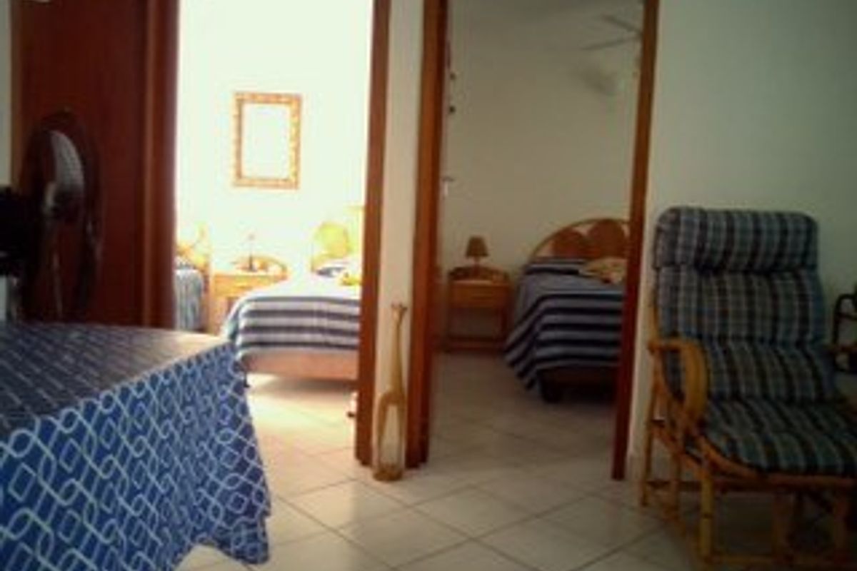 A view looking through a doorway into a bedroom area with tiled flooring and wooden door frames.