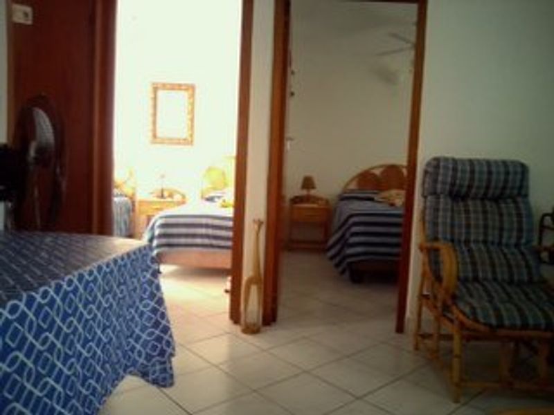 A view looking through a doorway into a bedroom area with tiled flooring and wooden door frames.