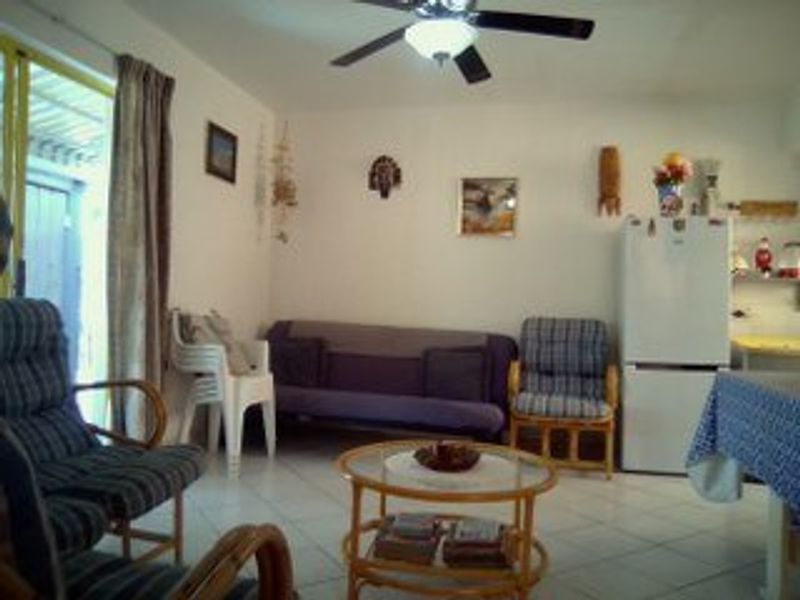 A living room area featuring tiled flooring, a ceiling fan, and access to an outdoor space via a sliding glass door.