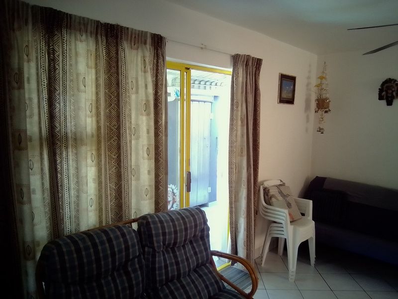 A living room area featuring tiled flooring, a ceiling fan, and a sliding glass door providing access to an outdoor space.