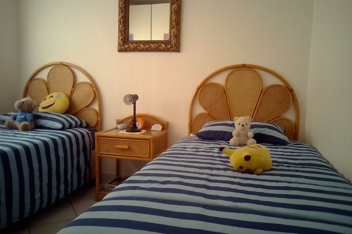 A bedroom featuring tiled flooring and neutral wall finishes, currently configured with twin beds.